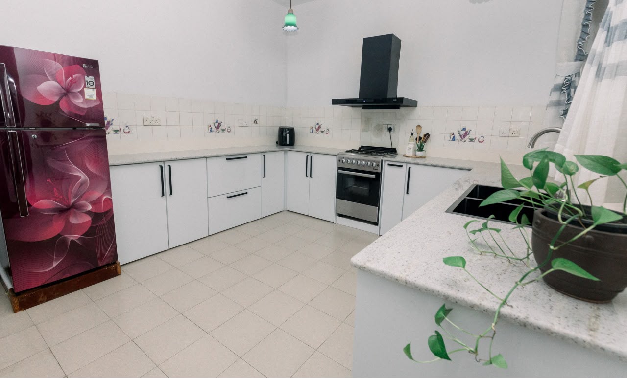 White L-shaped kitchen with black handles and chimney